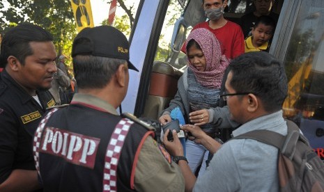 Anggota Satuan Polisi Pamong Praja (Satpol PP) memeriksa kartu identitas penumpang bus saat inspeksi penduduk pendatang pada arus balik H+4 Lebaran di Terminal Ubung, Denpasar, Selasa (21/7). 