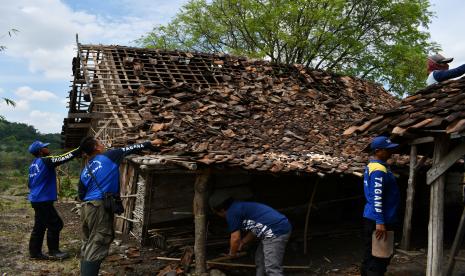 Anggota Taruna Siaga Bencana (Tagana) merapikan genteng pada rumah yang rusak akibat puting beliung di Desa Sumberbendo, Saradan, Kabupaten Madiun, Jawa Timur, Senin (18/10/2021). Puting beliung menyertai hujan di wilayah tersebut mengakibatkan tiga rumah warga roboh dan ratusan rusak serta banyak pohon tumbang, Minggu (17/10).