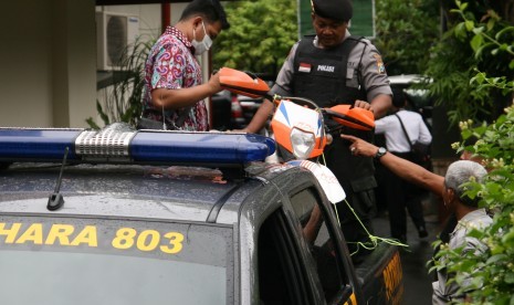 Anggota tim Komisi Pemberantasan Korupsi (KPK) dibantu polisi menaikkan sepeda motor ke atas mobil guna diamankan saat proses penggeledahan oleh KPK di rumah dinas bupati di Nganjuk, Jawa Timur, Senin (5/12).