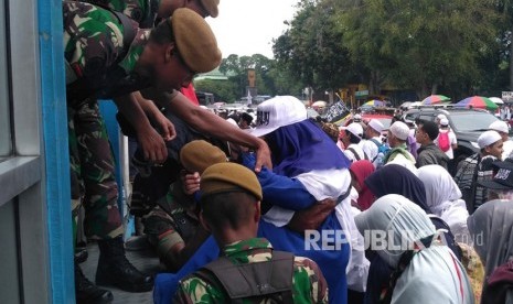 Anggota TNI membantu massa aksi Reuni 212 menyeberang jalan melewati halte Juanda, Ahad (2/12).