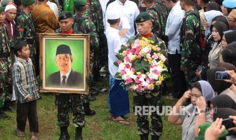 Anggota TNI membawa foto Almarhum KH. Hasyim Muzadi saat proses pemakaman di komplek Pondok Pesantren Al-Hikam, Depok, Jabar, Kamis (16/3).