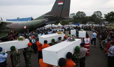 Anggota TNI membawa peti jenazah ke dalam pesawat untuk diterbangkan ke Surabaya.