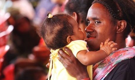 Seorang ibu bercanda dengan anaknya sebelum melakukan pemeriksaan kesehatan bayi di salah satu Posyandu di Papua. 