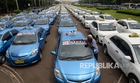 Angkutan umum diparkir di halaman Monas saat ribuan sopir melakukan aksi di depan Balai Kota DKI Jakarta, Senin (14/3).