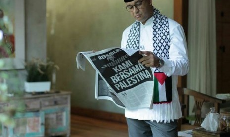 Anies Baswedan mengenakan syal berbendara Palestina sambil membaca koran Republika, Jumat (8/12).