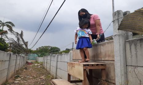 Anna Melinda Munir (30 tahun) bersama anaknya keluar dari rumah ibunya, Hadiyanti yang dikelilingi tembok, yang dibangun Haji Rulli di Kampung Brebes, Kelurahan Tajur, Kecamatan Ciledug, Kota Tangerang, Banten, Sabtu (13/3). 