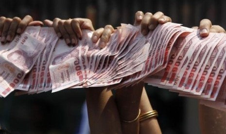 Anti-government protesters hold Thai baht banknotes to donate to protest leader Suthep Thaugsuban (unseen) as he leads a march through central Bangkok March 28, 2014.