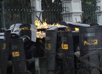 Aparat kepolisian berlindung dari lemparan molotov saat terjadi bentrok antara pengunjuk rasa dengan polisi di kawasan Gambir, Jakarta, Selasa (27/3). 