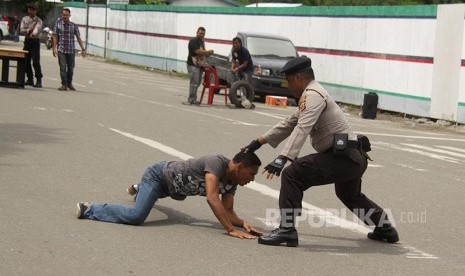 Aparat kepolisian berupaya melumpuhkan seorang perusuh saat simulasi penanganan kerusuhan Pilkada Aceh di Banda Aceh, Aceh, Sabtu (22/10). Simulasi tersebut dilaksanakan untuk meningkatkan kesiapan aparat keamanan dalam menghadapi berbagai kemungkinan gang