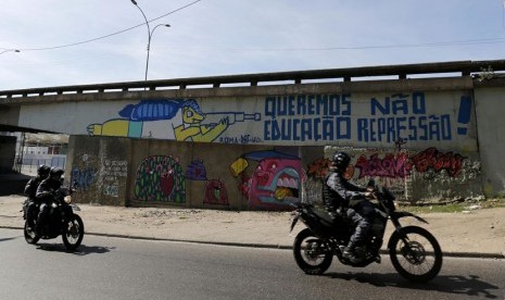  Aparat kepolisian melewati sebuah grafiti maskot Piala Dunia 2014, Fuleco, di salah satu sudut kota Rio de Janeiro. 