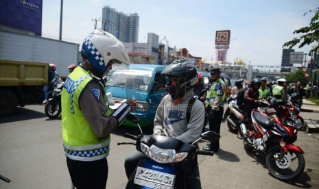  Aparat kepolisian memeriksa kelengkapan surat kendaraan pengendara motor saat menggelar operasi Zebra Jaya 2014 di Jalan Margonda Raya, Depok, Jumat (28/11).    (Republika/Raisan Al Farisi)