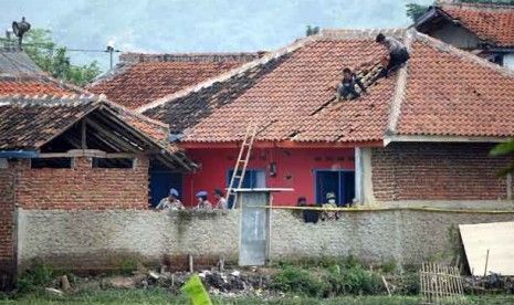   Aparat Kepolisian memperbaiki kerusakaan di rumah lokasi penangkapan teroris di Cigondewah Hilir, Marga Asih, Kabupaten Bandung, Kamis (9/5).