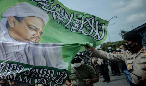 Aparat kepolisian mengamankan banner HRS saat unjuk rasa 1812 Front Pembela Islam (FPI) di sekitar Patung Kuda Arjuna Wiwaha, Jakarta Pusat, Jumat (18/12). Polisi memukul mundur massa yang menolak dibubarkan guna menghindari kerumunan. Sebanyak 5.000 personel gabungan dari unsur TNI-Polri dan Pemprov DKI Jakarta disiapkan untuk mengawal dan mengamankan unjuk rasa 1812 di kawasan Istana Negara.