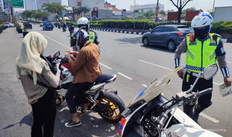 Aparat Satuan Lalu Lintas Polres Metro (Satlantas Polrestro) Depok menindak pengendara motor yang melanggar di Jalan Margonda Raya, Kota Depok.