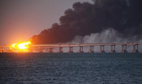 Api dan asap membubung dari Jembatan Krimea yang menghubungkan daratan Rusia dan semenanjung Krimea di atas Selat Kerch, di Kerch, Krimea, Sabtu, 8 Oktober 2022. Pihak berwenang Rusia mengatakan sebuah bom truk telah menyebabkan kebakaran dan runtuhnya sebagian jembatan yang menghubungkan Rusia -mencaplok Krimea dengan Rusia. Tiga orang telah tewas. Jembatan itu adalah arteri pasokan utama bagi upaya perang Moskow yang goyah di Ukraina selatan.