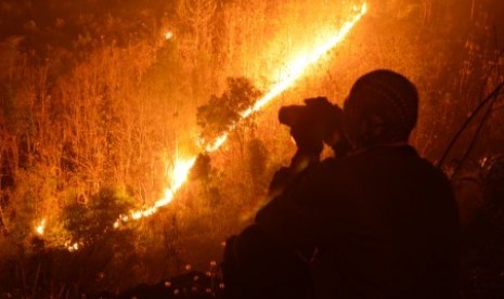 Api membakar kawasan hutan di lereng Gunung Wilis terlihat dari Desa Kresek, Wungu, Madiun, Jumat (23/10) malam. 