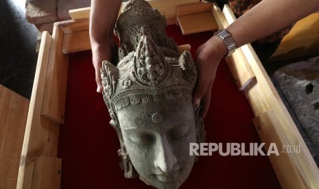 Arkeolog Dinas Kebudayaan dan Pariwisata memasukkan potongan kepala arca Bodhisatwa yang baru saja ditemukan ke dalam kotak kaca di Museum Bhagawanta Bari, Kediri, Jawa Timur, Rabu (17/7/2019). 