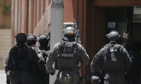 Armed police stand at the ready close to a cafe under siege at Martin Place in Sydney, Australia, Monday, Dec. 15, 2014. 