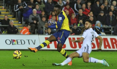 Arsenal's Danny Welbeck (L) shoots past Swansea City's Neil Taylor during their English Premier League soccer match at the Liberty Stadium in Swansea, Wales November 9, 2014.