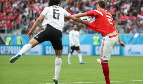  Artem Dzyuba (Rusia) berebut bola dengan Ahmed Hegazy (Mesir) dalam laga kedua Grup A Piala Dunia 2018, di Saint Petersburg Stadium, Rabu (20/6) dini hari.