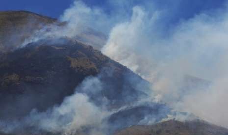 Asap mengepul dari kebakaran hutan gunung Sindoro difoto dari Desa Sigedang, Kejajar, Wonosobo, Tengah, Sabtu (8/9). Kebakaran sejak Jumat (7/9) siang tersebut terjadi di lahan hutan dan ilalang yang berada pada petak 7B area Perhutani KPH Kedu Utara, Canggal, Candiroto, Temanggung dan masih dalam proses pemadaman oleh Perhutani, BPBD dan masyarakat.