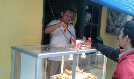 Asep sedang berjualan di depan kosnya. 