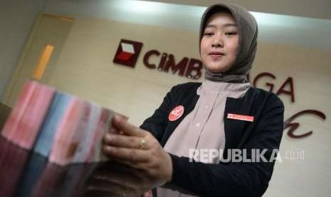 Aset Perbankan Syariah. Petugas menghitung setotan nasabah di kantor layanan CIMB Niaga Syariah, Jakarta, Selasa (18/9). Sampai pertengahan 2018 pangsa aset industri keuangan syariah mencapai 8,5 persen dari total aset industri keuangan di Indonesia. 