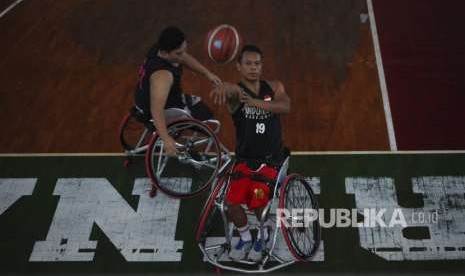 Atlet disabilitas cabang Wheelchair Basketball Indonesia Idrus (kiri) melempar bola ke ring saat mengikuti pemusatan latihan Asian Para Games di GOR Sritex Solo, Jawa Tengah, Rabu (26/9).