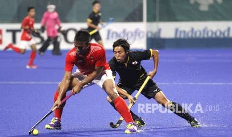 Atlet Hoki Jepang, Murata Kazuma (kanan) berebut bola dengan atlet Indonesia, Hakim Wahid (kiri) dalam babak penyisihan grup Hoki putra Asian Games 2018 di Lapangan Hoki, Komplek Gelora Bung Karno, Jakarta, Rabu (22/8). 