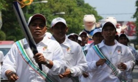 Atlet karate Arif Taufan Samsudin (kiri) bersama sejumlah atlet Sulsel, membawa obor SEA Games, keliling kota Makassar, Sulsel, Senin (31/10). 