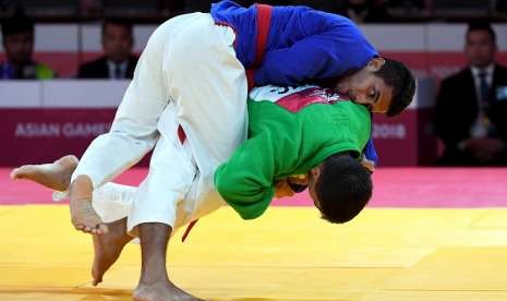 Atlet kurash Indonesia Aprilianda Adi Timur (atas) melakukan serangan pada atlet kurash Uzbekistan Maruf Gaybulloev (bawah) saat bertanding pada babak 32 besar putra -66kg Asian Games 2018 di Assembly Hall JCC Senayan, Jakarta, Selasa (28/8).