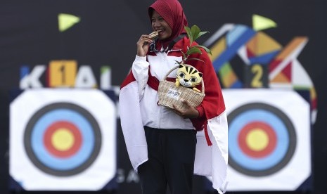 Atlet panahan Indonesia Diananda Choirunnisa menggigit medali emas ketika upacara penganugerahan medali panahan nomor recurve putri di Synthetic Turf Fild, Kawasan Bukit Jalil, Malaysia, Minggu (20/8). 