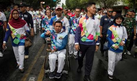 Atlet Paragames, Jaenal Aripin (tengah) bersama Ketua INAPGOC, Raja Sapta Oktohari (kedua kanan) membawa lentera api pada Pawai Api Obor Asian Para Games 2018 di Solo, Jawa Tengah.