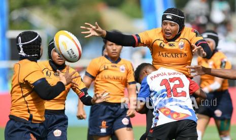 Atlet rugby putri DKI Jakarta Pipit Ayu Lestari (kanan) melempar bola ke arah rekannya yang dihadang atlet rugby putri Papua Inha Yahmin (tengah bawah) saat bertanding pada final Rugby 7s Putri PON Papua di Lapangan Rugby AURI, Kabupaten Jayapura, Papua, Rabu (13/10/2021). Pada pertandingan tersebut tim rugby putri DKI Jakarta menang atas Papua dengan skor 12-10, dan berhasil merebut medali emas sedangkan Papua perak.