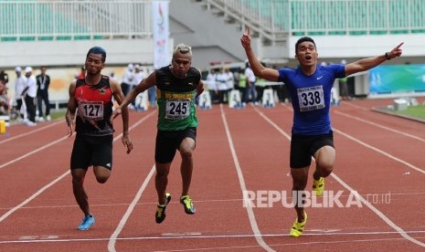 Atlet Sumatra Barat Yaspi Boby (kanan) mengangkat tangan saat memenangkan lari 100 meter putra di Stadion Pakansari, Cibinong, Jawa Barat, Kamis (22/9). 