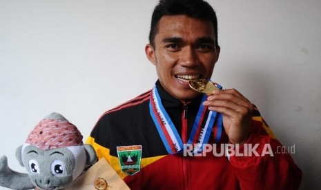 Atlet Sumatra Barat, Yaspi Boby mengigit medali usai penyerahan medali lari nomor 100 meter putra di stadion Pakansari, Cibinong, Jawa Barat, Kamis (22/9).