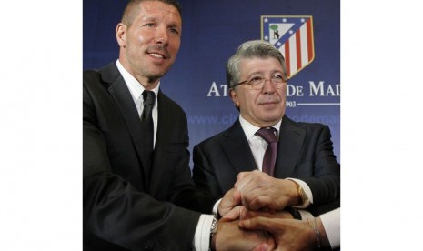 Atletico de Madrid's new soccer coach Diego 'Cholo' Simeone from Argentina, left, shakes hands with club president Enrique Cerezo, right, during his official presentation at the Vicente Calderon stadium in Madrid, Spain, Tuesday, Dec. 27, 2011.