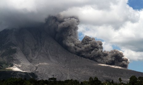 Awan panas meluncur dari puncak Gunung Sinabung ketika terjadi guguran kubah lava terlihat dari Desa Tiga Pancur, Karo, Sumatera Utara, Minggu (10/1).