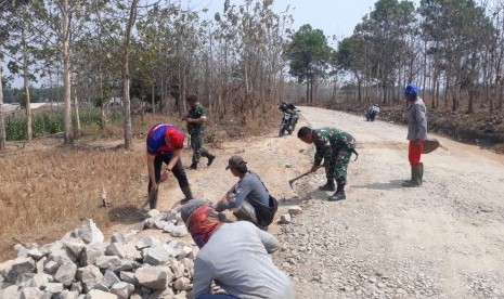 Anggota TNI dibantu warga saat melakukan pengerasan jalan yang merupakan salah satu kegiataan TMMD.