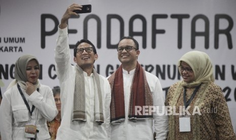 Bakal Calon Gubernur DKI Anies Baswedan (kedua kanan) dan Bakal Cawagub Sandiaga Uno (kedua kiri) didampingi istri berswafoto usai menyerahkan dokumen pendaftaran kepada pimpinan KPUD DKI saat pendaftaran di KPUD DKI Jakarta, Jumat (23/9) malam.