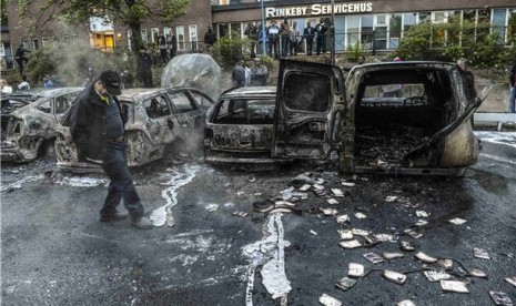 Bangkai mobil teronggok setelah massa membakarnya dalam kerusuhan yang terjadi di daerah pinggiran Rinkeby, Stockholm, Swedia, Kamis (23/5). 