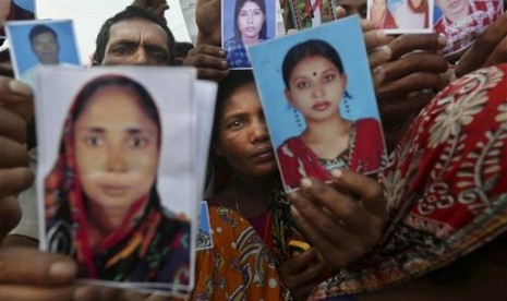 Bangladeshi relatives of workers missing in a building that collapsed Wednesday hold pictures of loved ones at a makeshift morgue in a schoolyard in Savar, near Dhaka, Bangladesh, Saturday, April 27, 2013. 