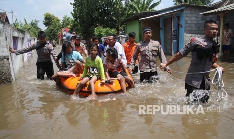 Petugas Badan Penanggulangan Bencana Daerah (BPBD) bersama anggota polisi mengevakuasi warga menggunakan perahu karet di kawasan yang terendam banjir. 