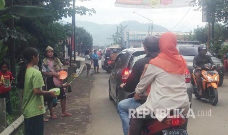 Seiring dengan banjir luapan Citarum, sejumlah orang meminta sumbangan di Jalan Bojongsoang, Kecamatan Dayeuhkolot, Kabupaten Bandung, Ahad (30/10). 