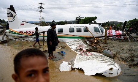 Banjir Sentani. Warga mengamati sebuah pesawat yang terseret banjir bandang di Sentani, Jaya Pura, Papua, Senin (18/3).