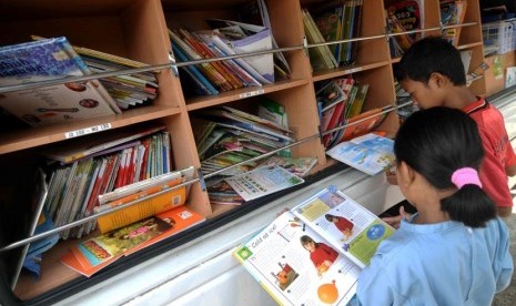 Bantu Minat Baca Anak. Beberapa anak membaca buku di mobil perpustakaan keliling di Penjaringan, Jakarta Utara, Jumat (21/3).