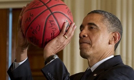 Barack Obama memegang bola basket. 