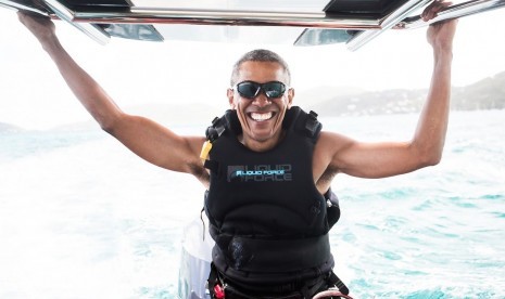 Barack Obama tersenyum saat menikmati liburan bersama Richard Branson.