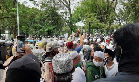 Barisan aparat hendak memukul mundur massa aksi 1812 di Jalan Merdeka Selatan, tepatnya  di depan kantor Kementerian BUMN, Jumat (18/12) pukul 13.50 WIB