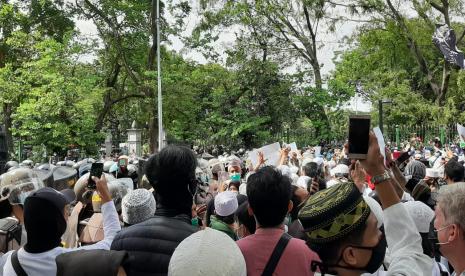 Barisan aparat hendak memukul mundur massa aksi 1812 di Jalan Merdeka Selatan, tepatnya  di depan kantor Kementerian BUMN, Jumat (18/12) pukul 13.50 WIB.